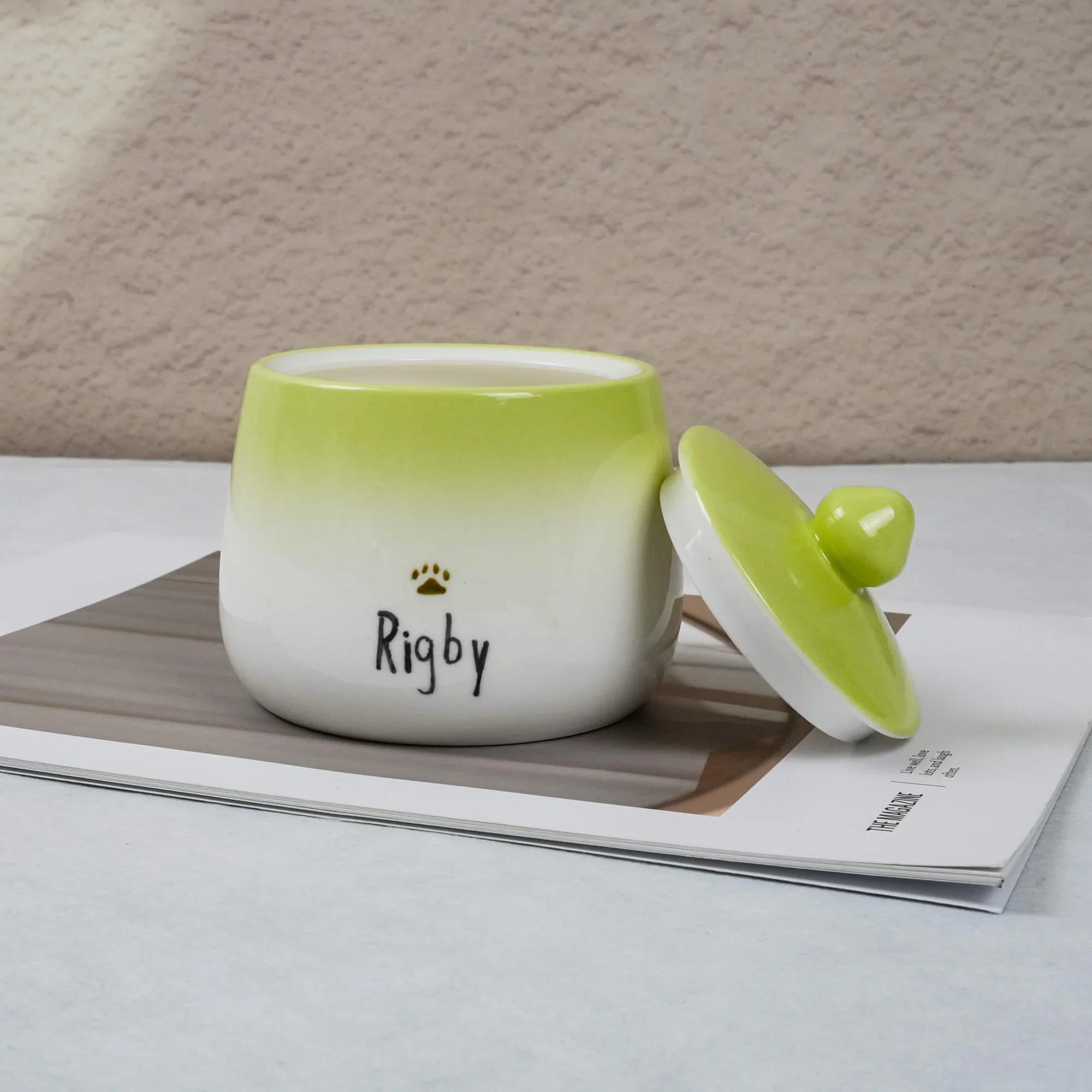 Green and white ceramic container with 'Rigby' on a magazine
