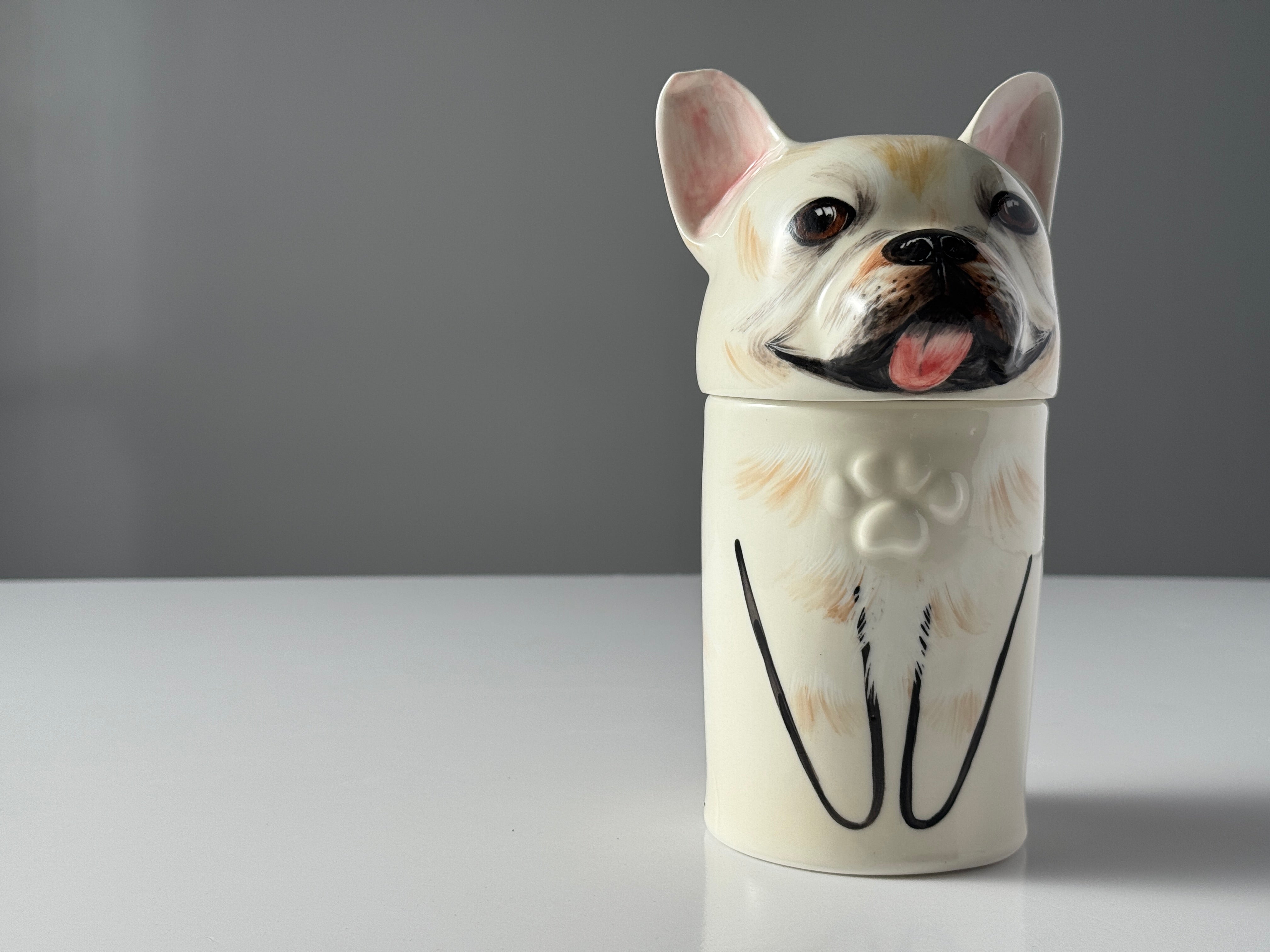 Ceramic jar shaped like a dog's head with a gray background