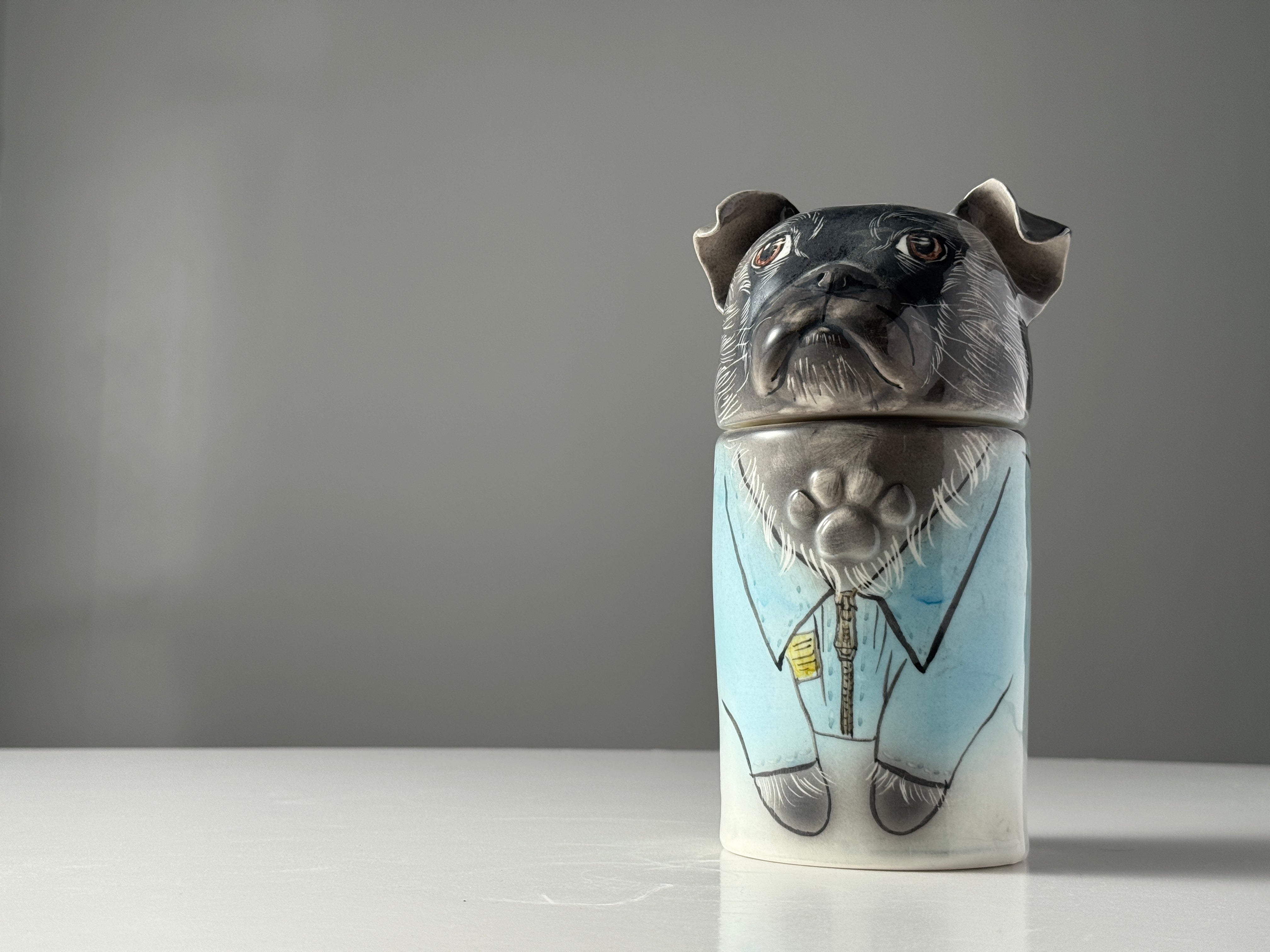 Ceramic container shaped like a dog with a gray background