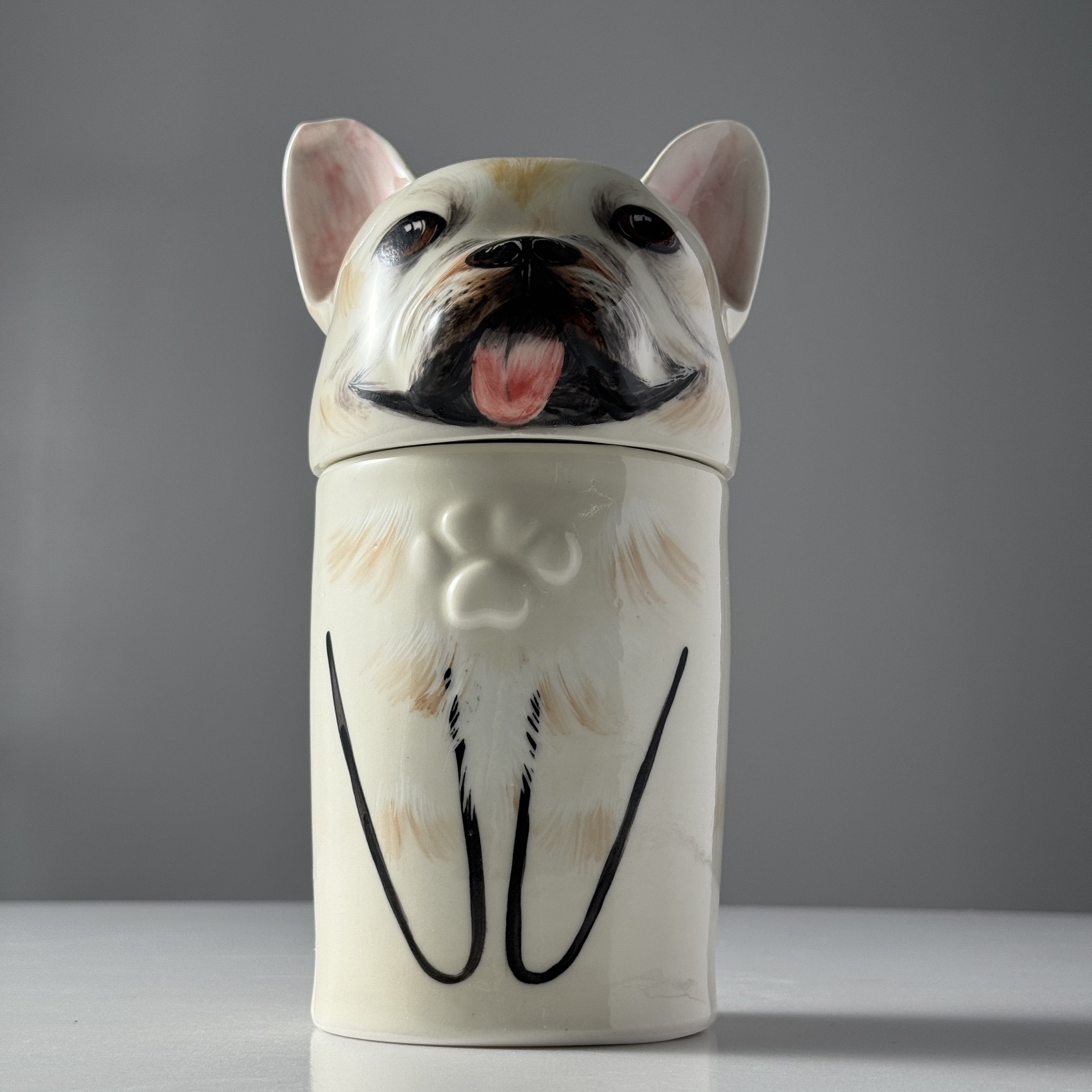 Ceramic jar shaped like a dog with a gray background