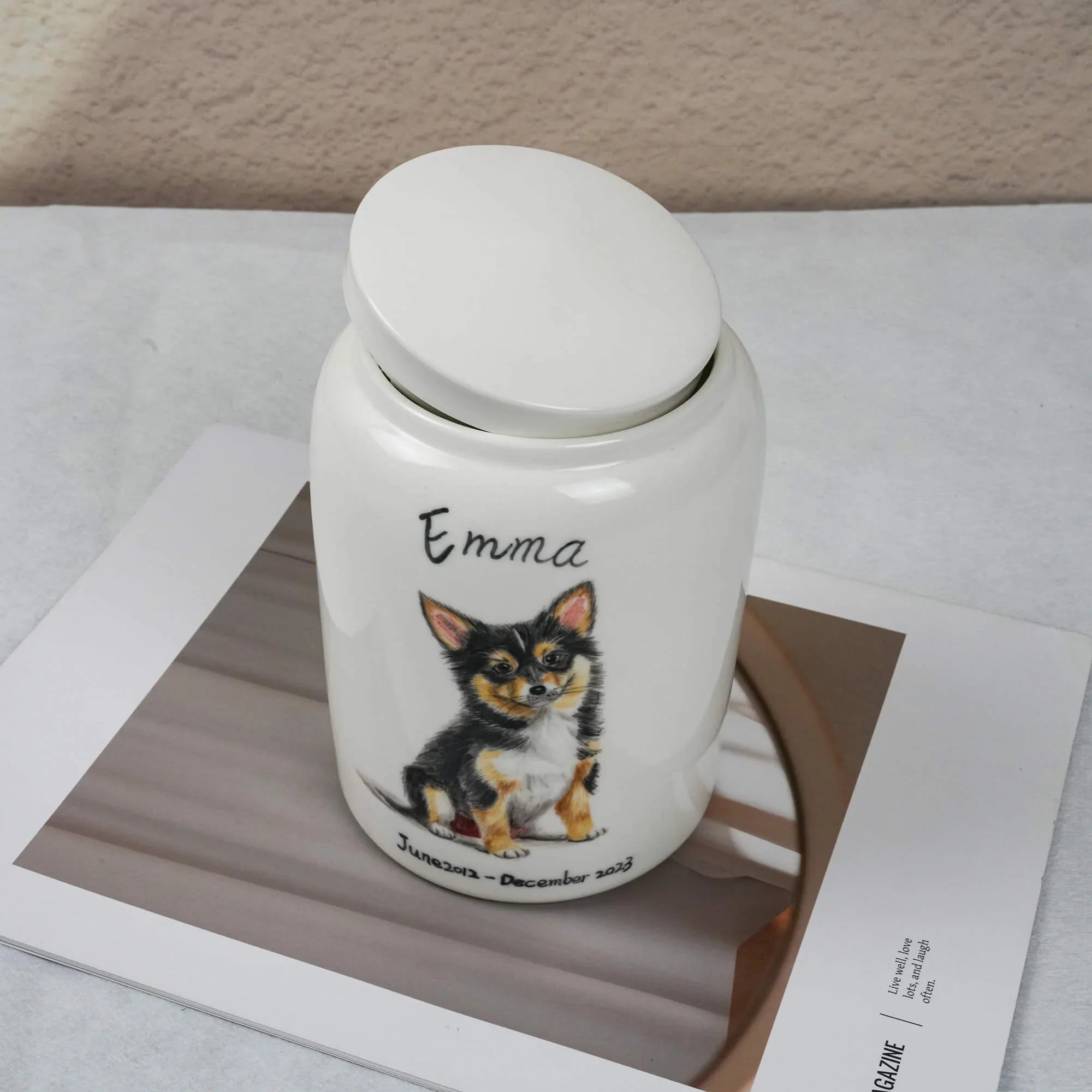 White urn with a dog illustration and 'Emma' text on a magazine