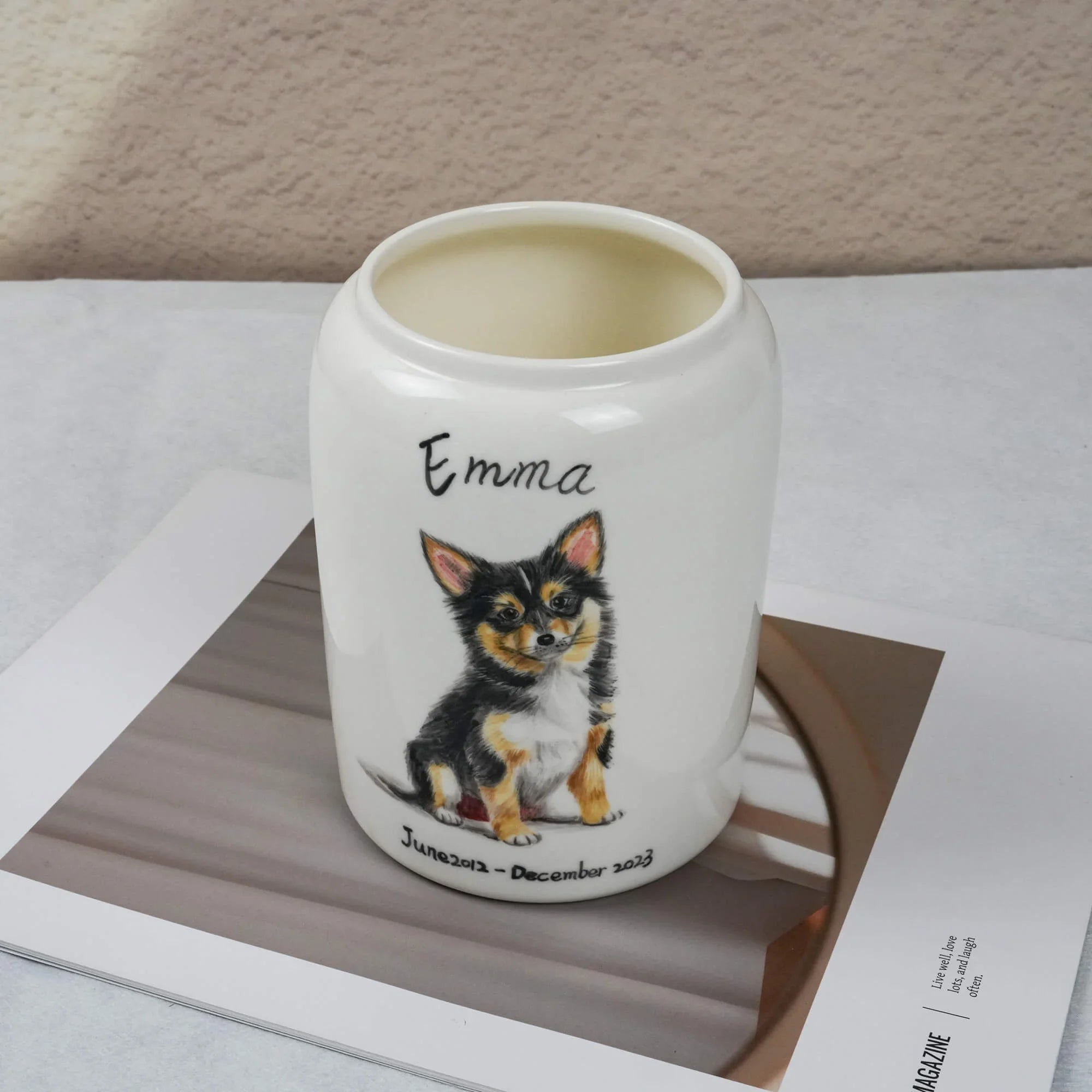 White mug with a dog illustration and name 'Emma' on a magazine