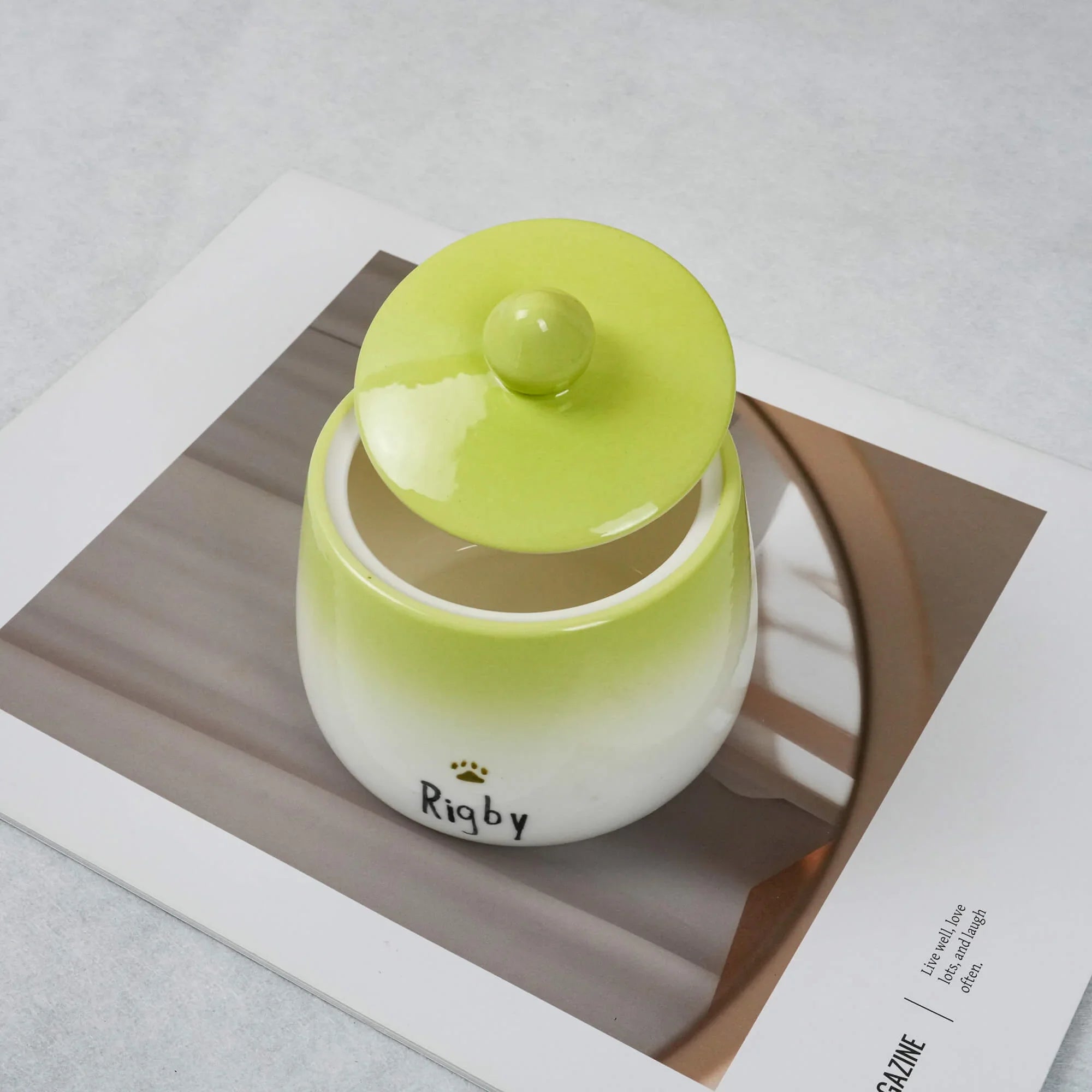 Small ceramic jar with a green lid on a magazine page