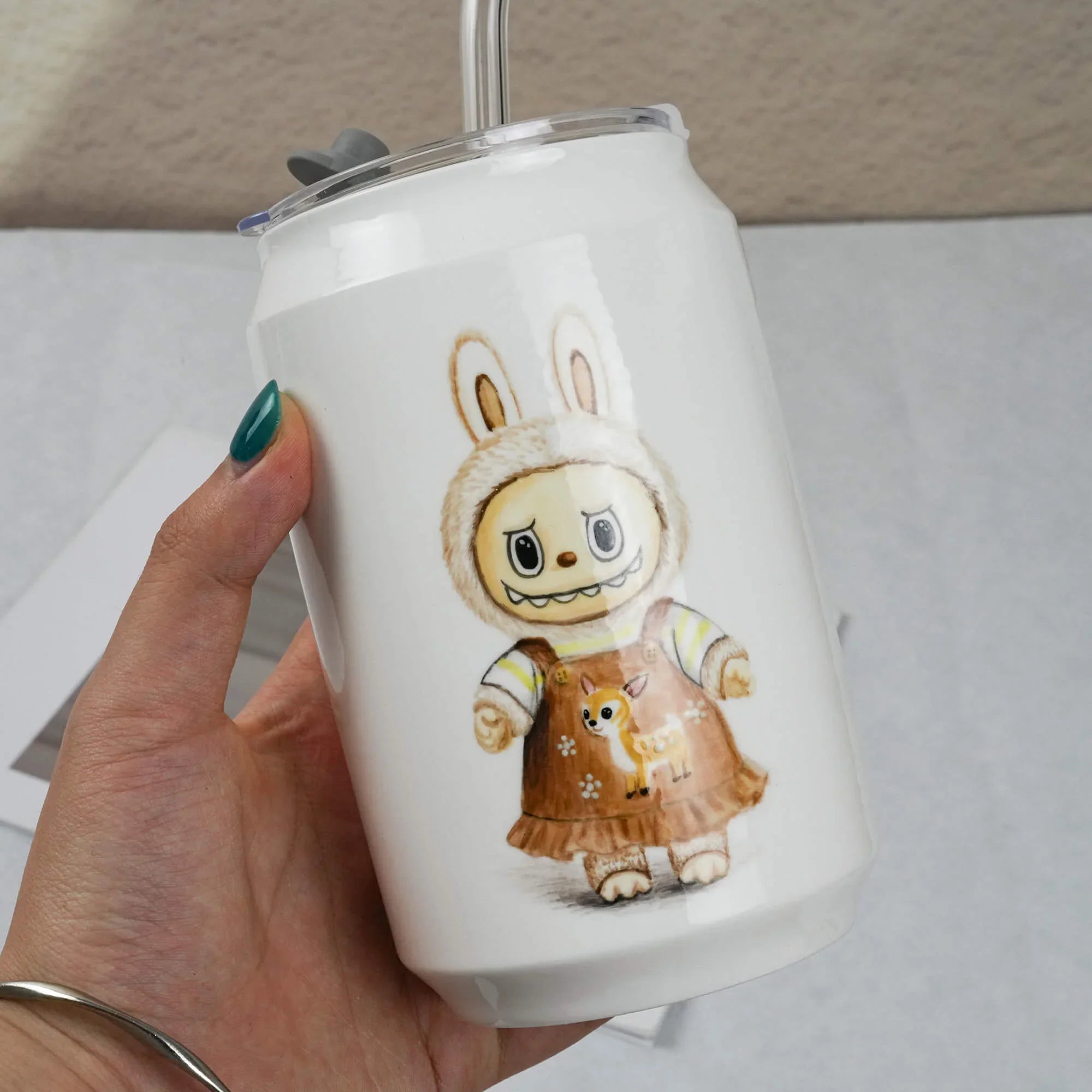 White tumbler with a cartoon character design held by a hand.