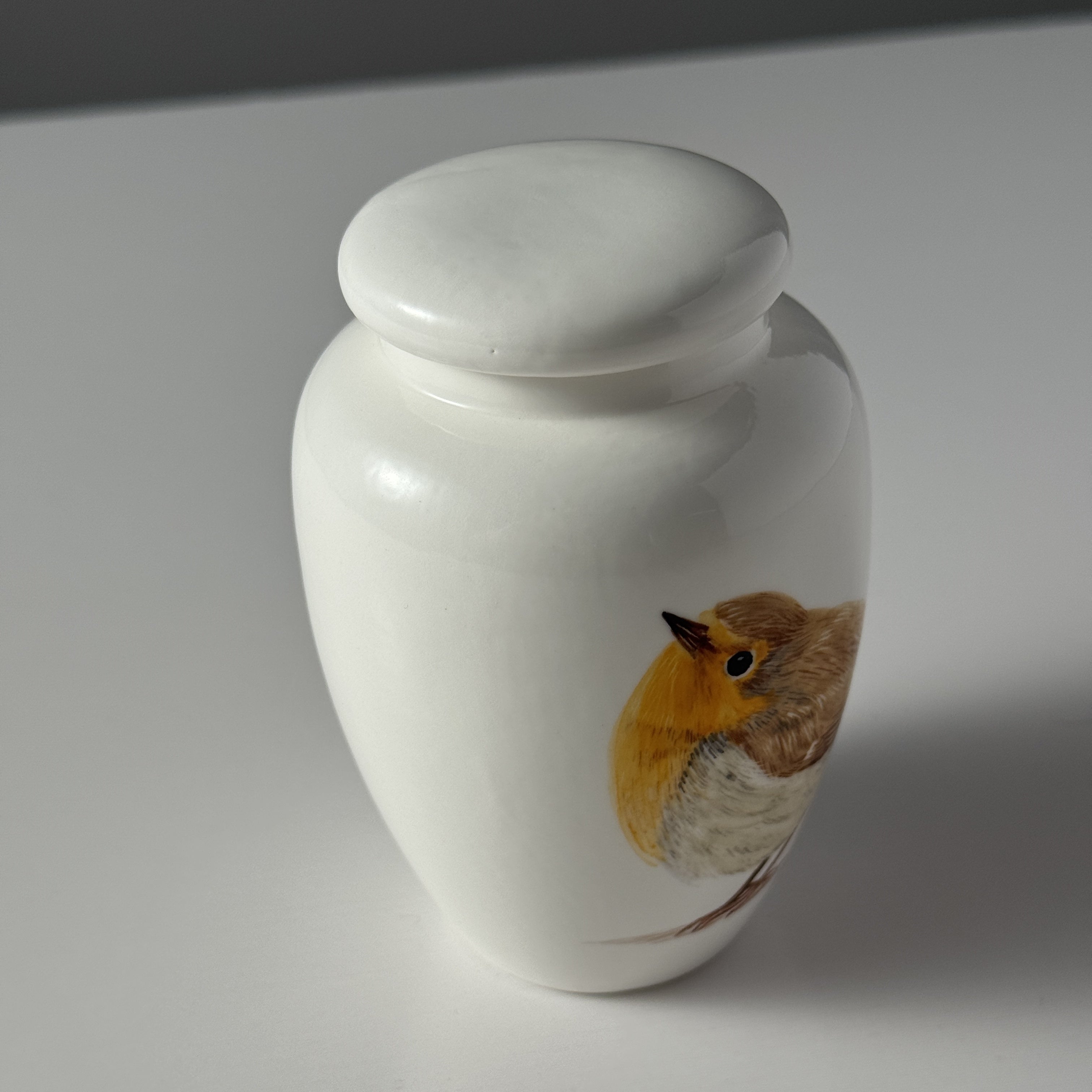 White urn with a bird design on a white background