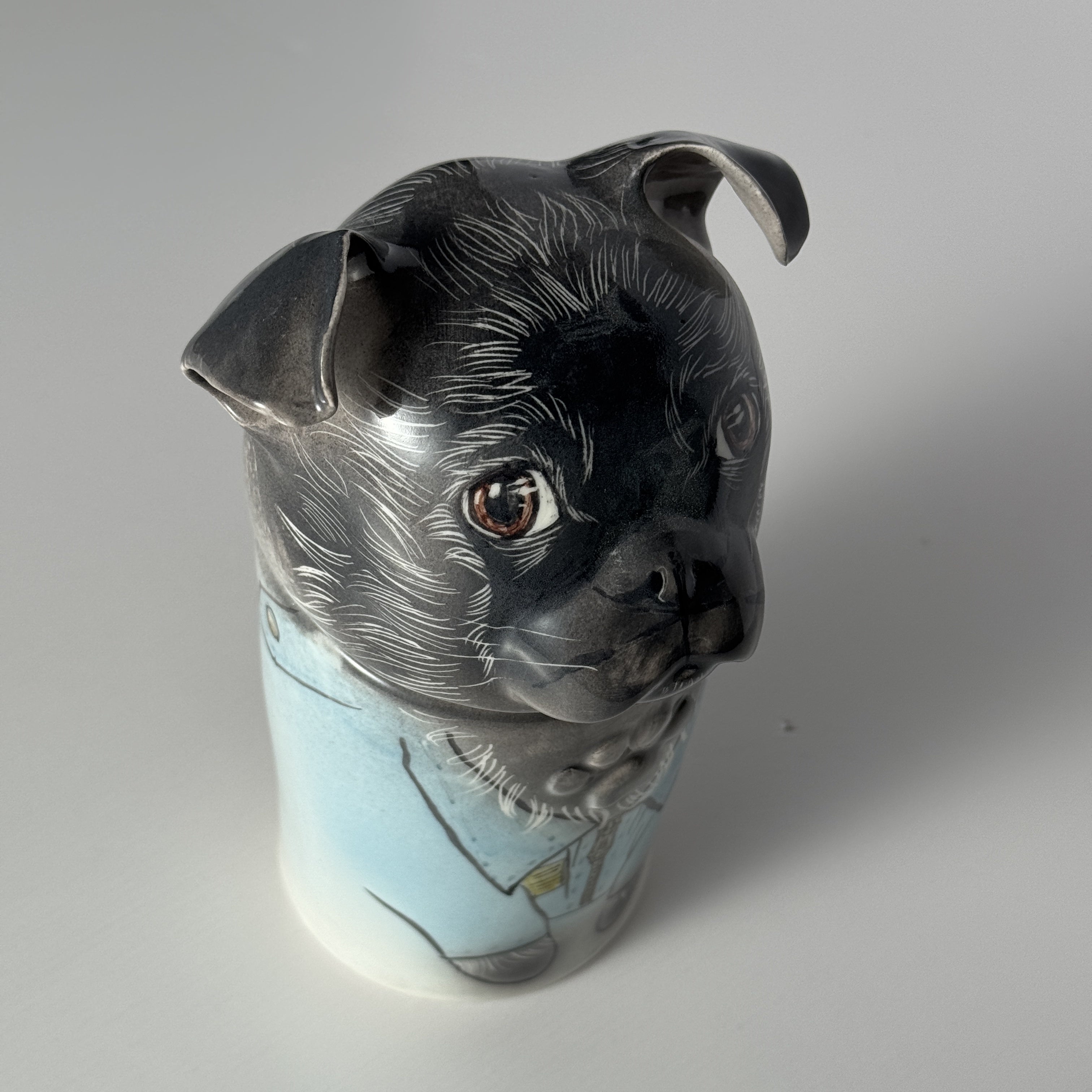 Vase shaped like a black dog's head on a plain background