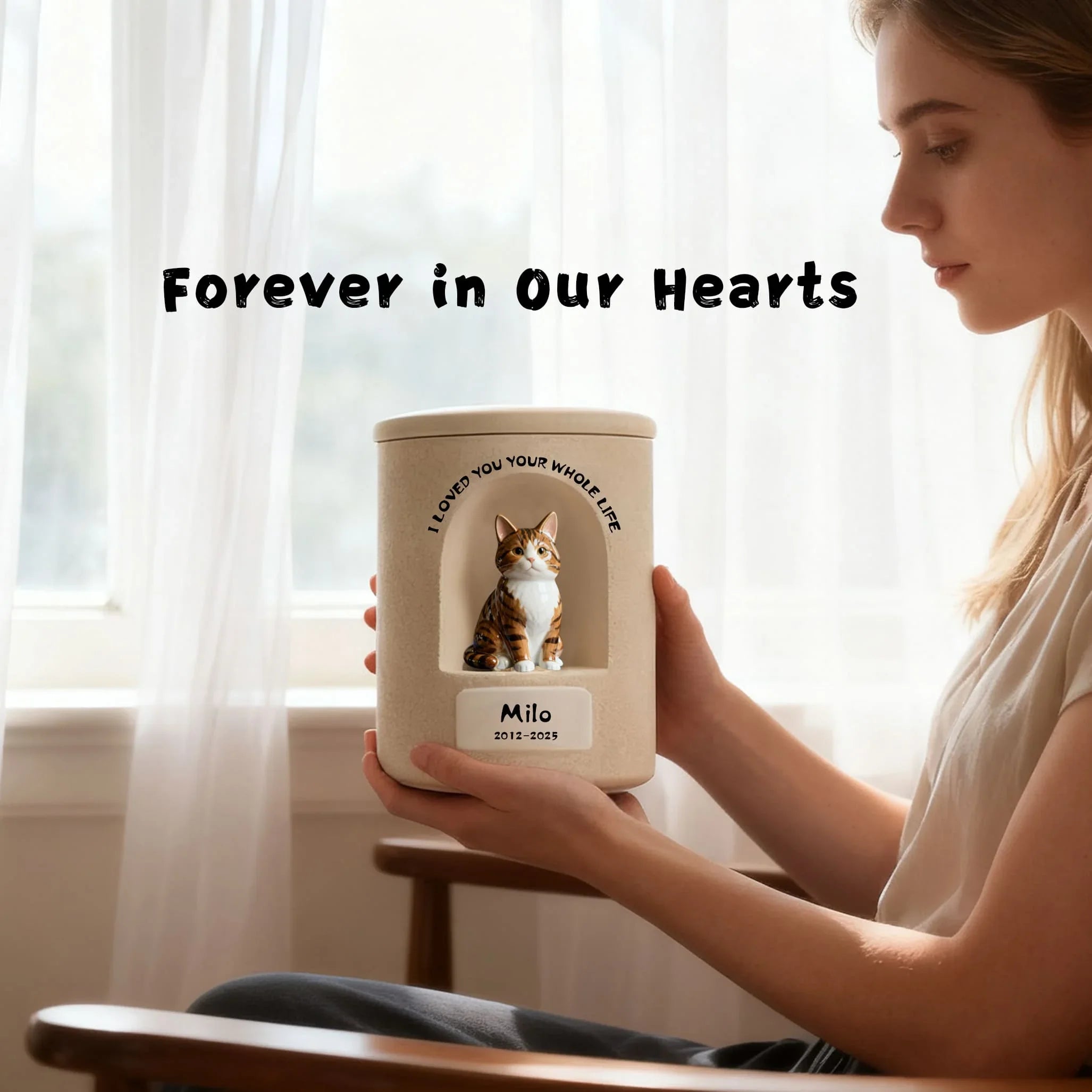 Person holding a pet urn with a cat's photo and text 'Forever in Our Hearts' in a softly lit room.